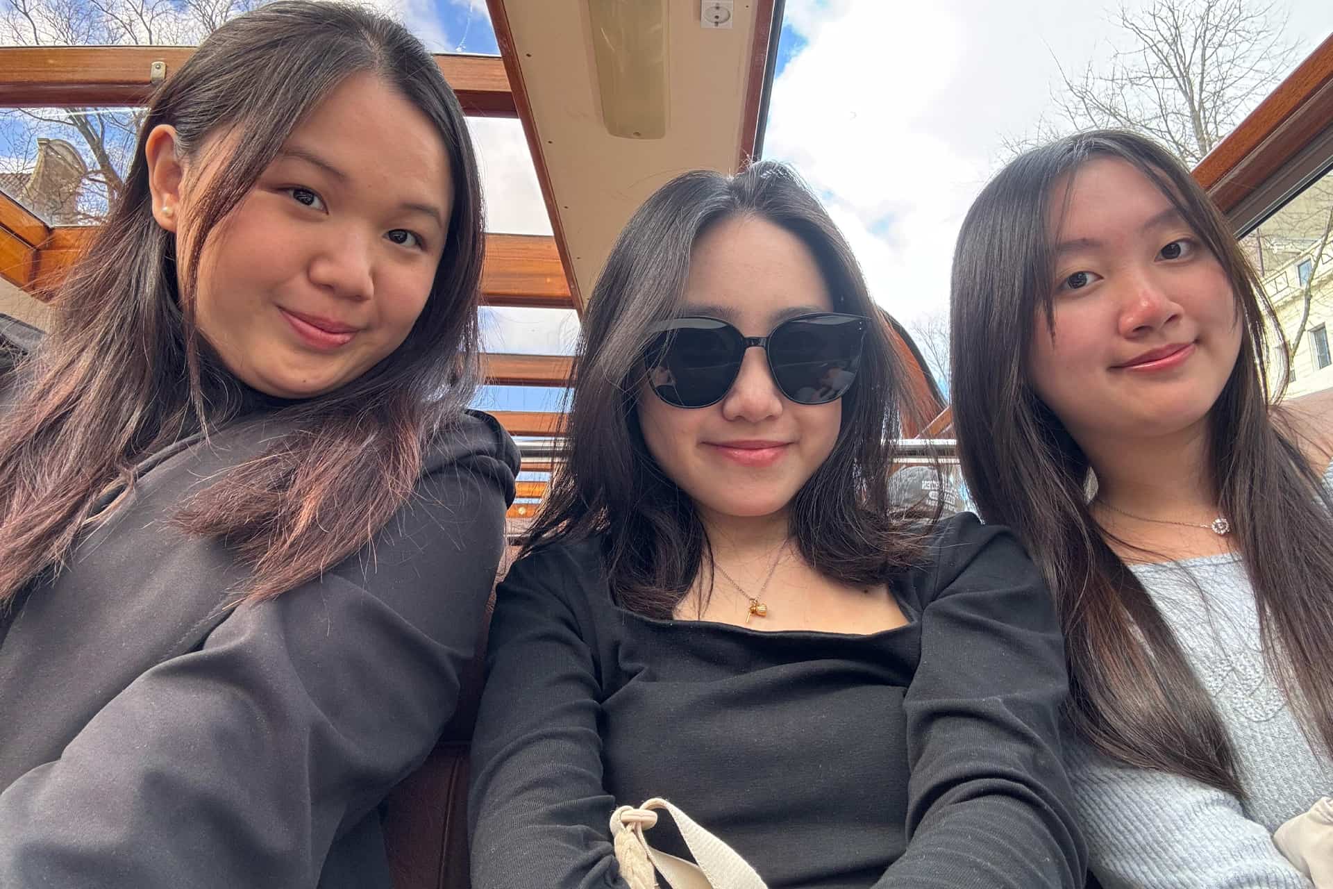 Three students sitting side by side on a boat.
