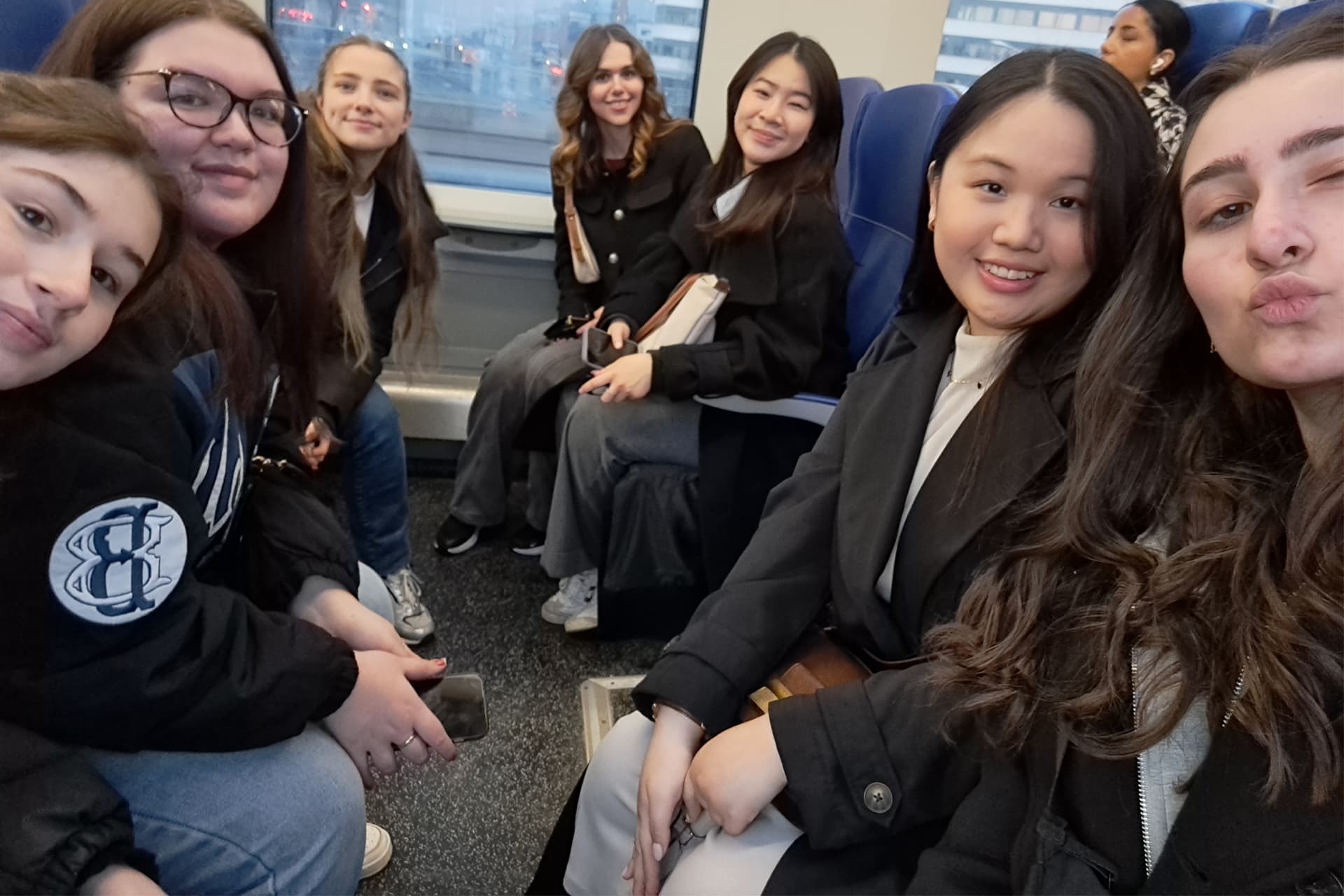 A group of students sitting together on a train smiling.