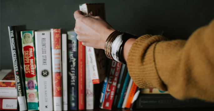 Grabbing a book from a shelf filled with books.