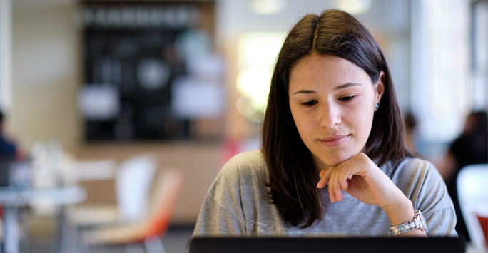 A student sits looking at her laptop.