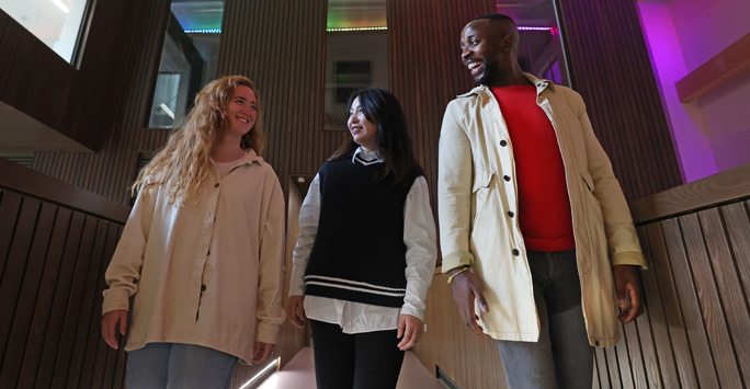 Three students walk together down a corridor.