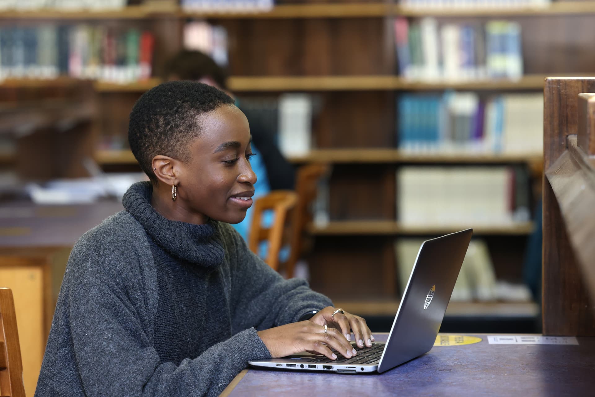 A student sits at a desk working on a laptop.