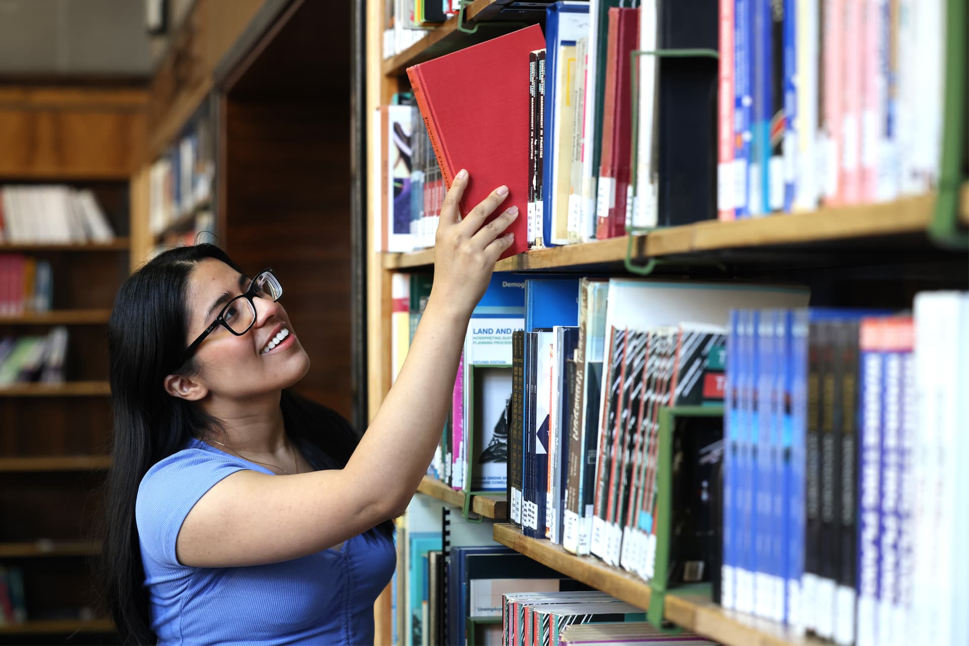 A student takes a book from a bookshelf filled with books.