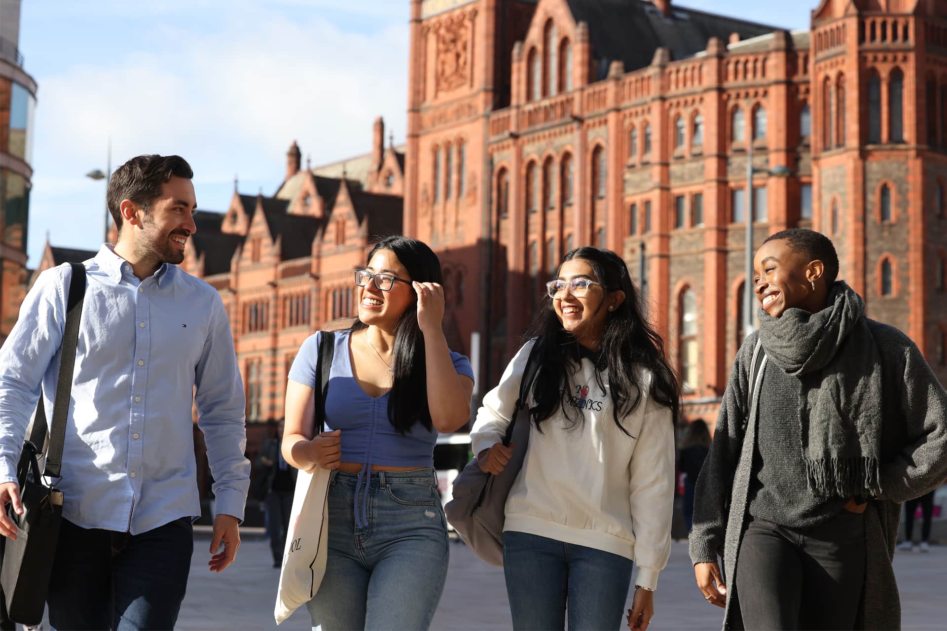 Four students walking through campus together smiling.