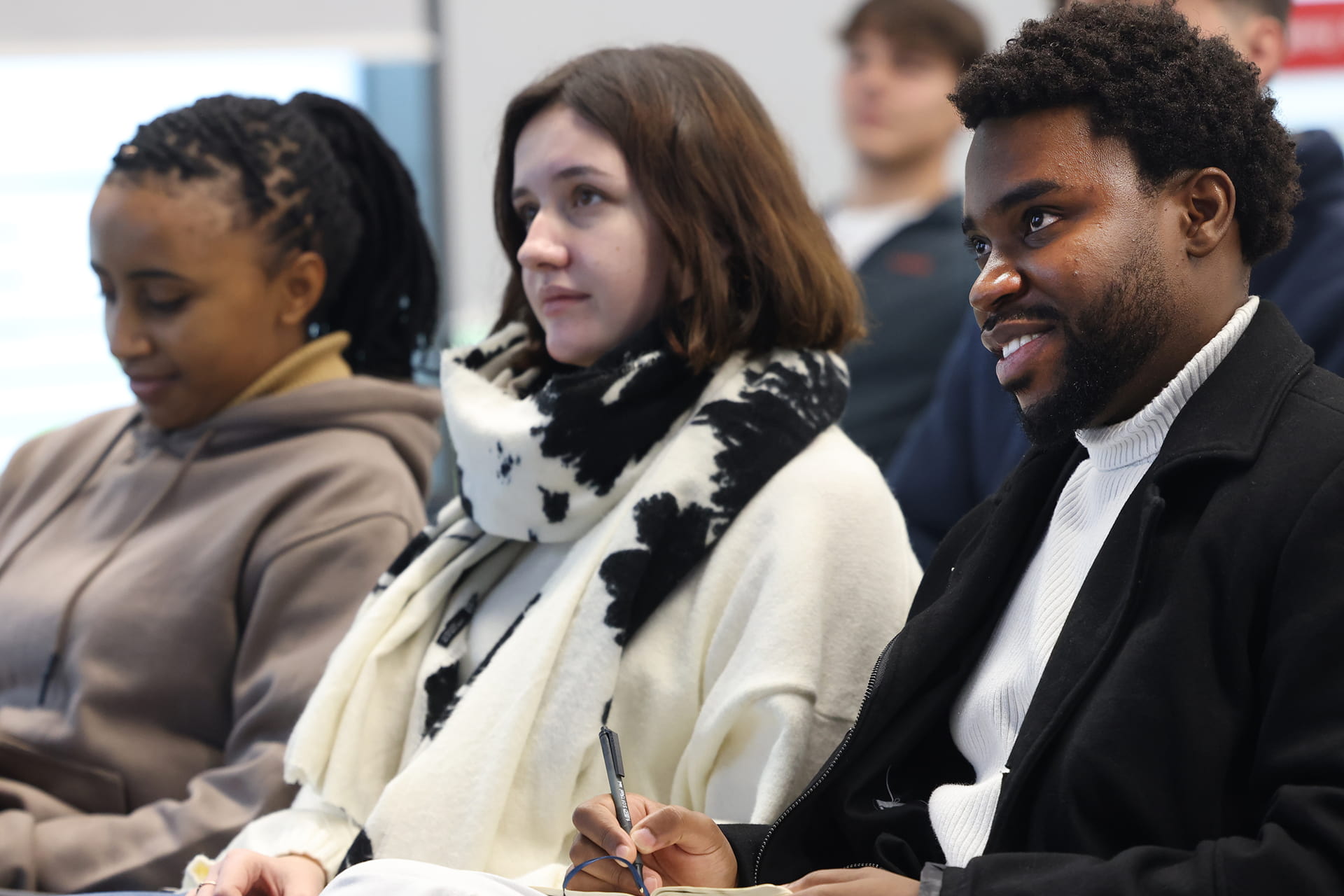 Students sit in rows, listening to a lecture in a classroom.