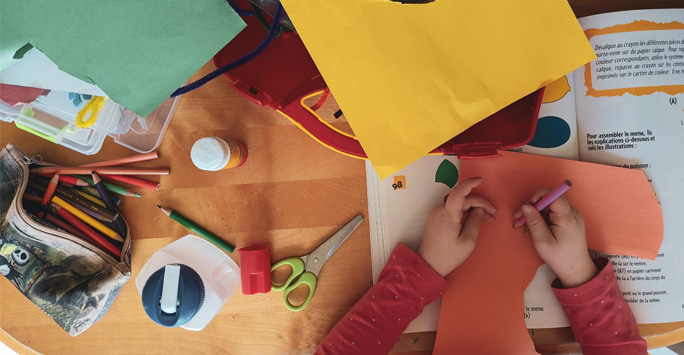 A child sat a table doing arts and crafts