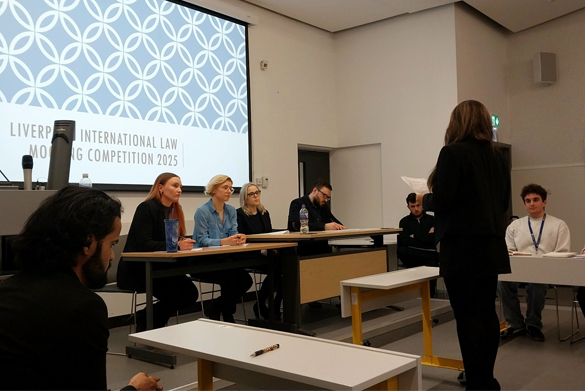 A student stands before a panel of judges, presenting their argument.