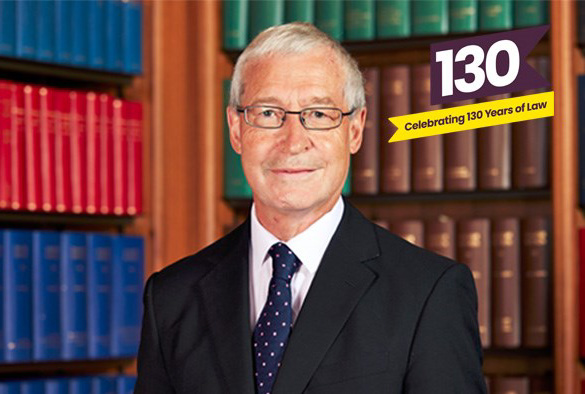 Supreme Court Judge Lord Burrows in front of book shelves. In the top-right corner is a logo for \'130 Years of Law\'