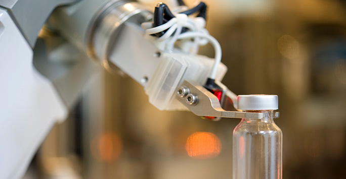 A robotic arm handling a vial in a laboratory setting.
