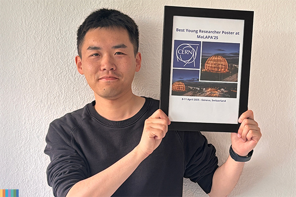 A person posing for a photo, holden a pictureframe with an award.