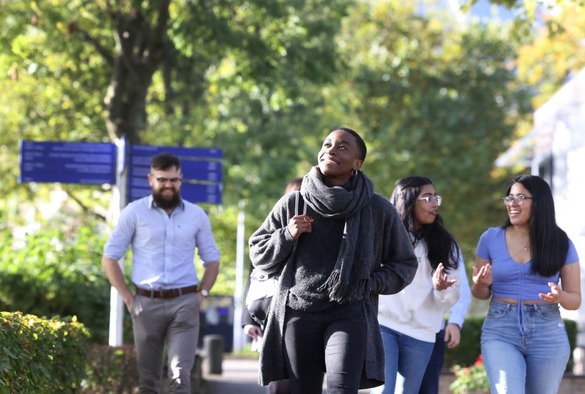 A diverse group of young people walking together on a sidewalk, engaged in conversation and enjoying their time outdoors.