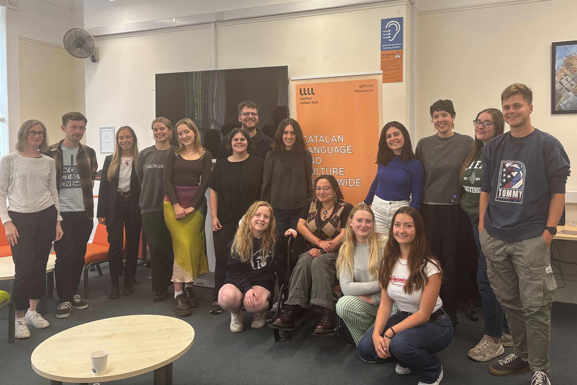 A group of people standing together in front of a banner from institut ramon llul.