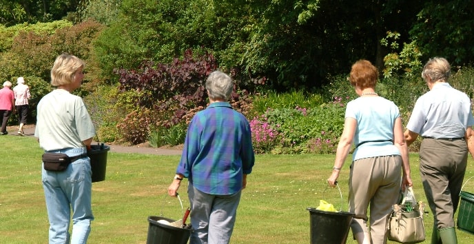 Volunteers with buckets walk across a grassed area