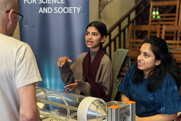 Two people talking to a visitor at an outreach event.