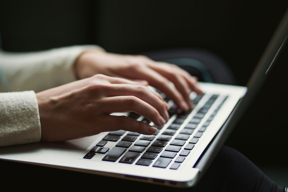 Hands typing on a laptop