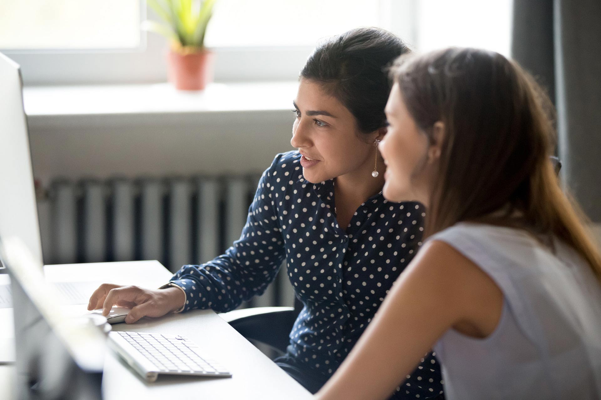 Two women working together and looking at computer screen
