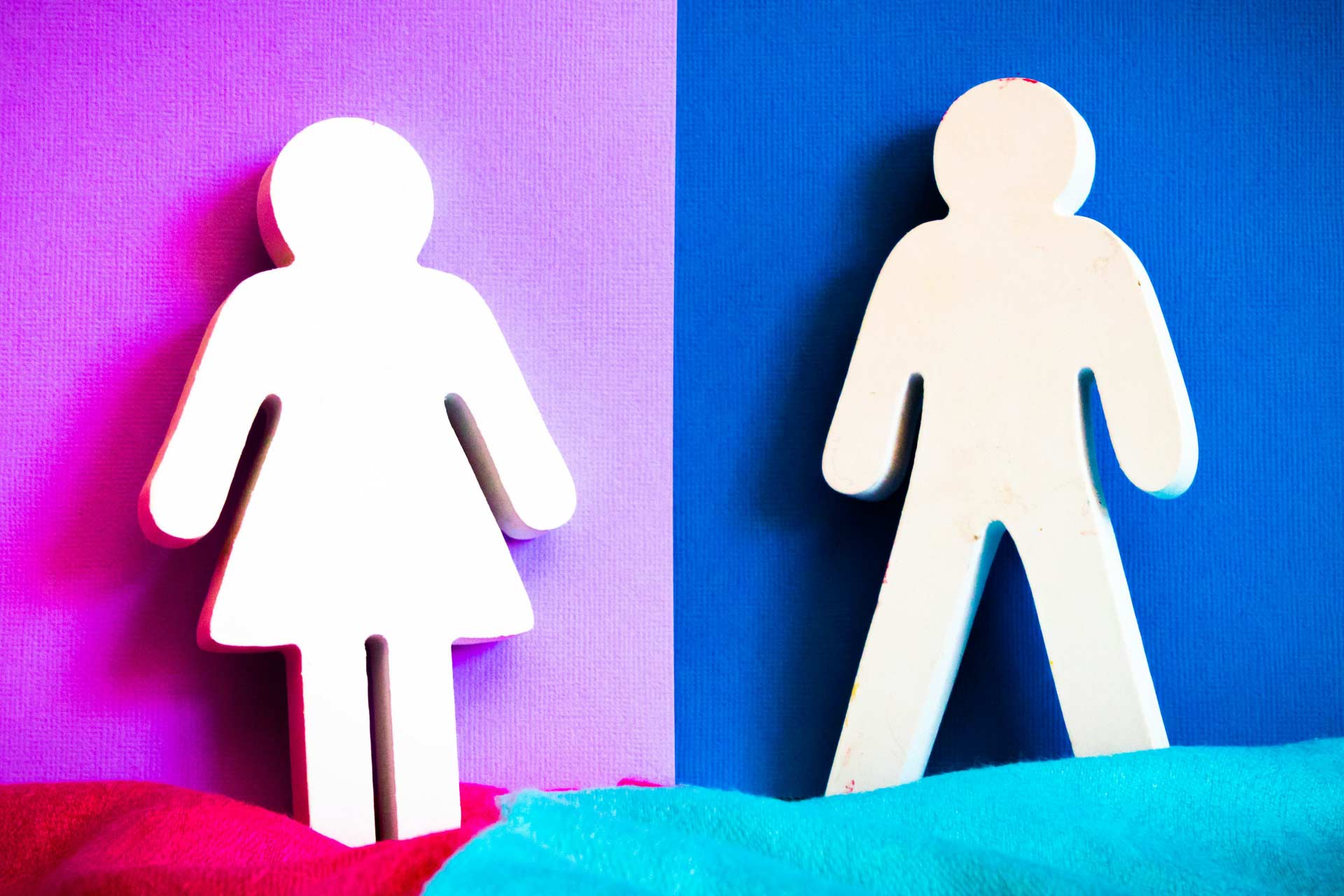 Female and male signs against pink and blue backgrounds representing traditional gender roles