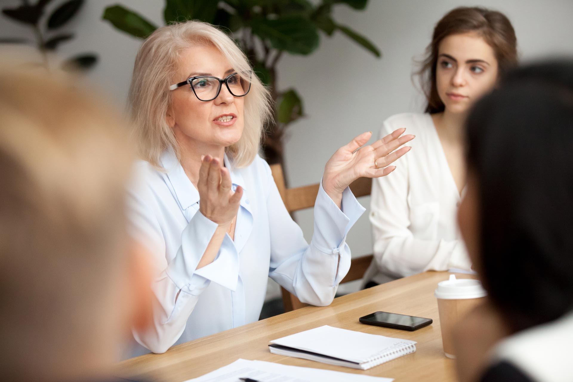 Middle aged business woman speaking to other females