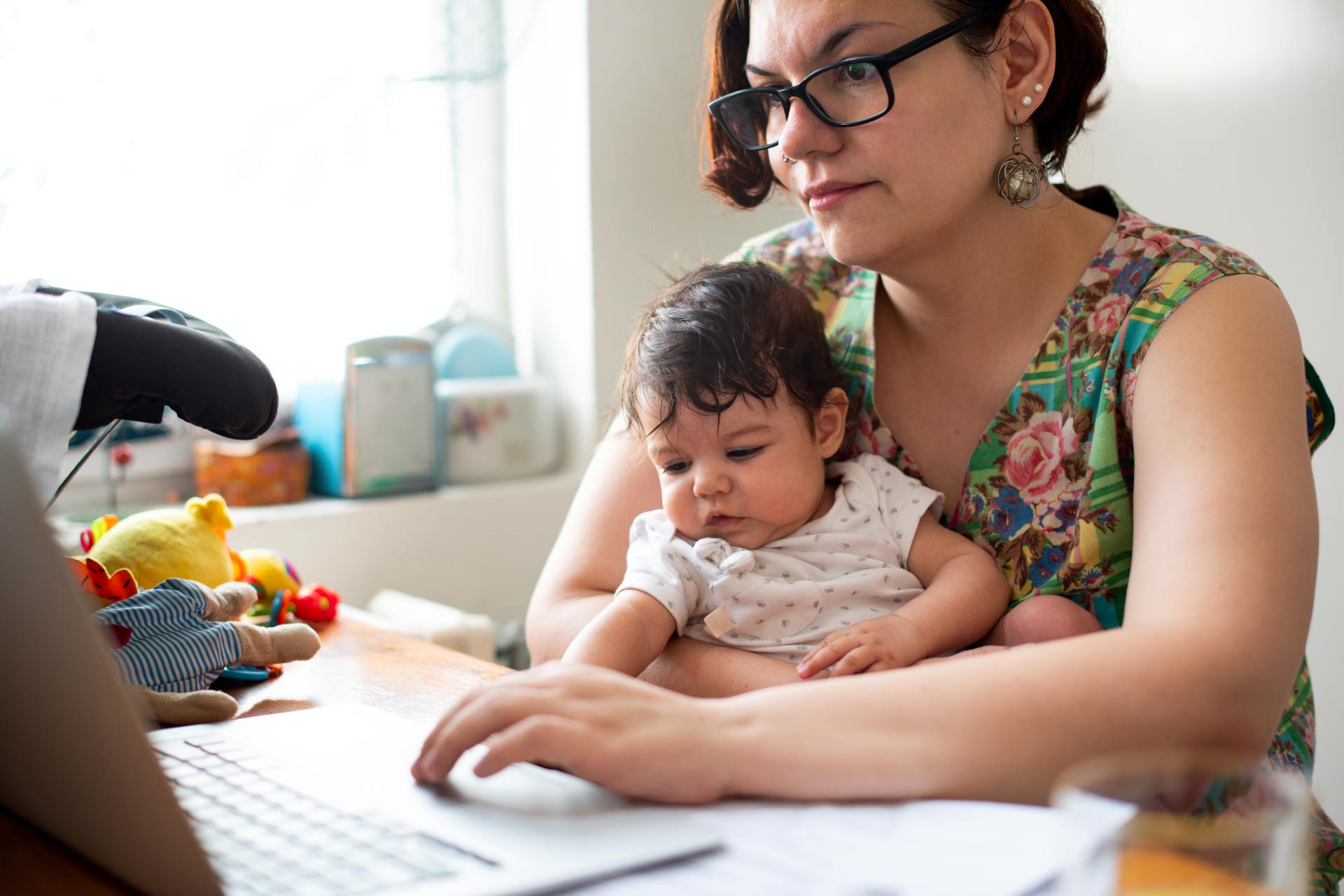 Mother working at home while holding baby