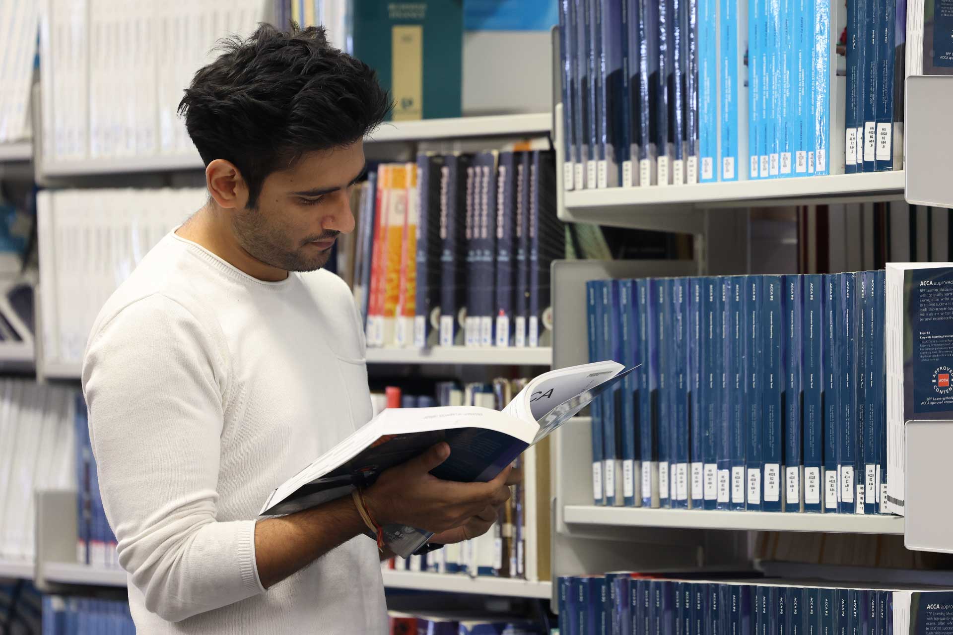 Male student reading a book in the library