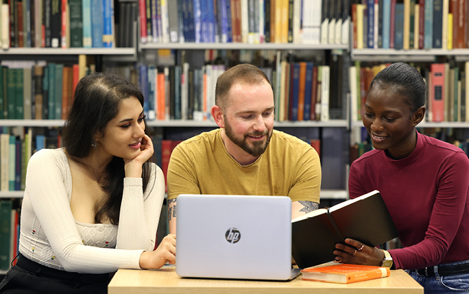Postgraduate research students in a conversation working around a laptop