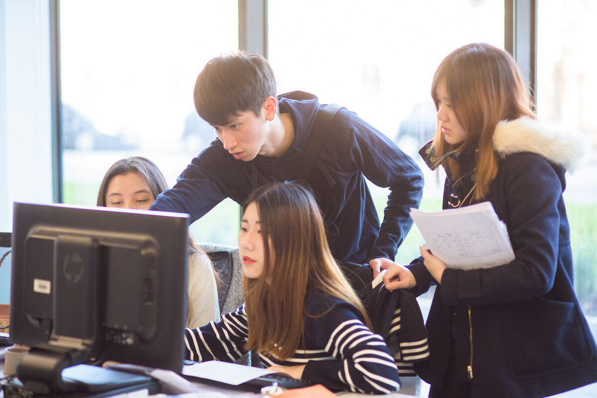 4 students using a desktop for group work