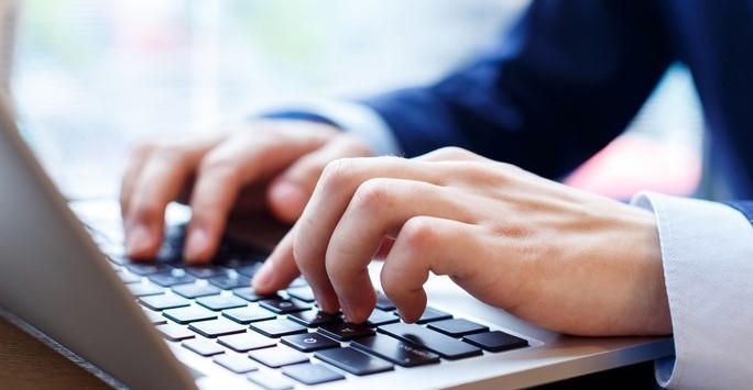 Person in a suit typing on a laptop computer