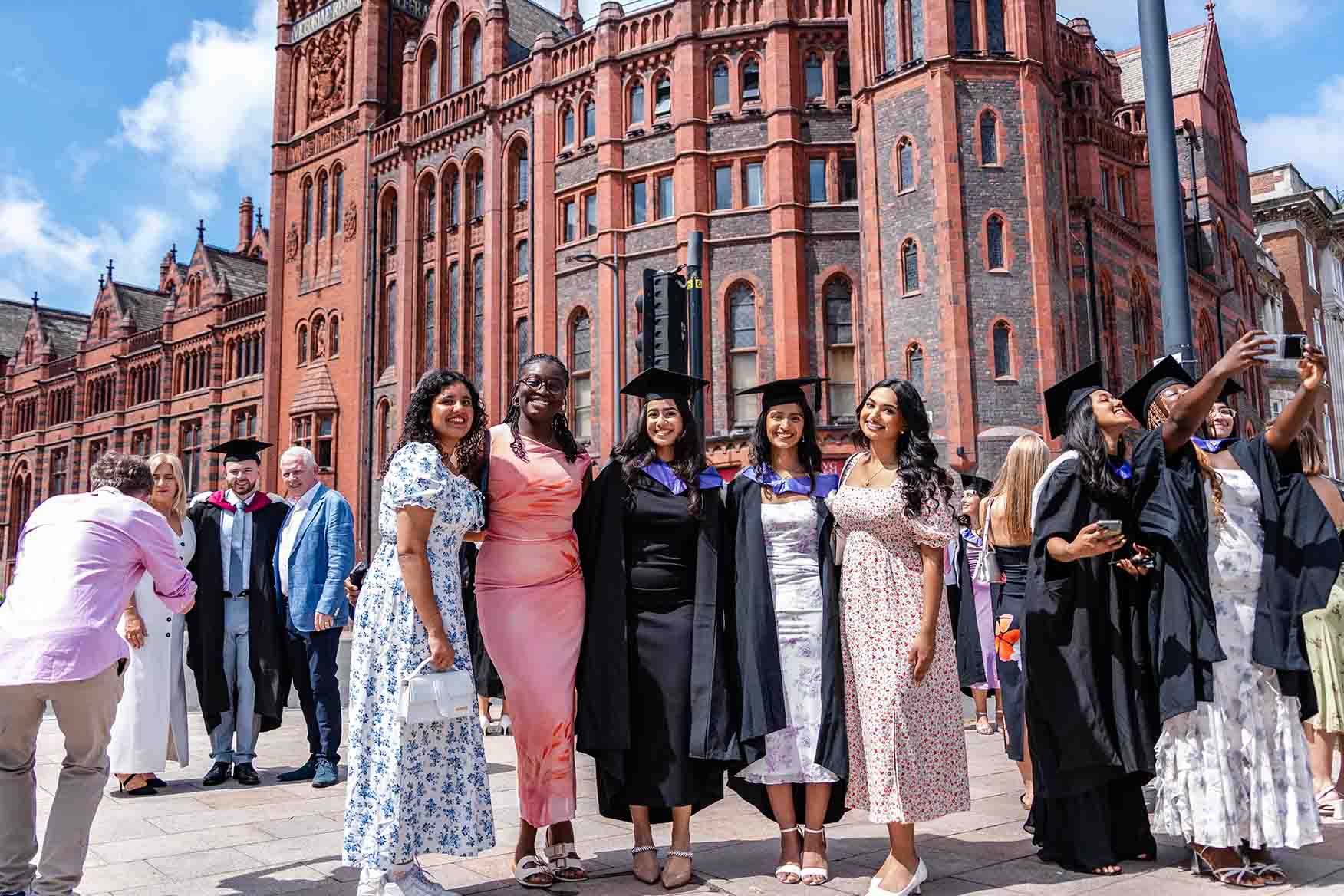 A group of graduating students celebrating in front of the main University building