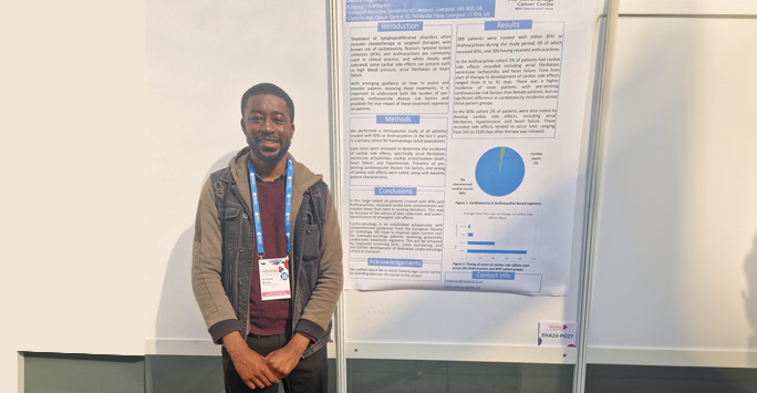 Student stands in front of his poster presentation board