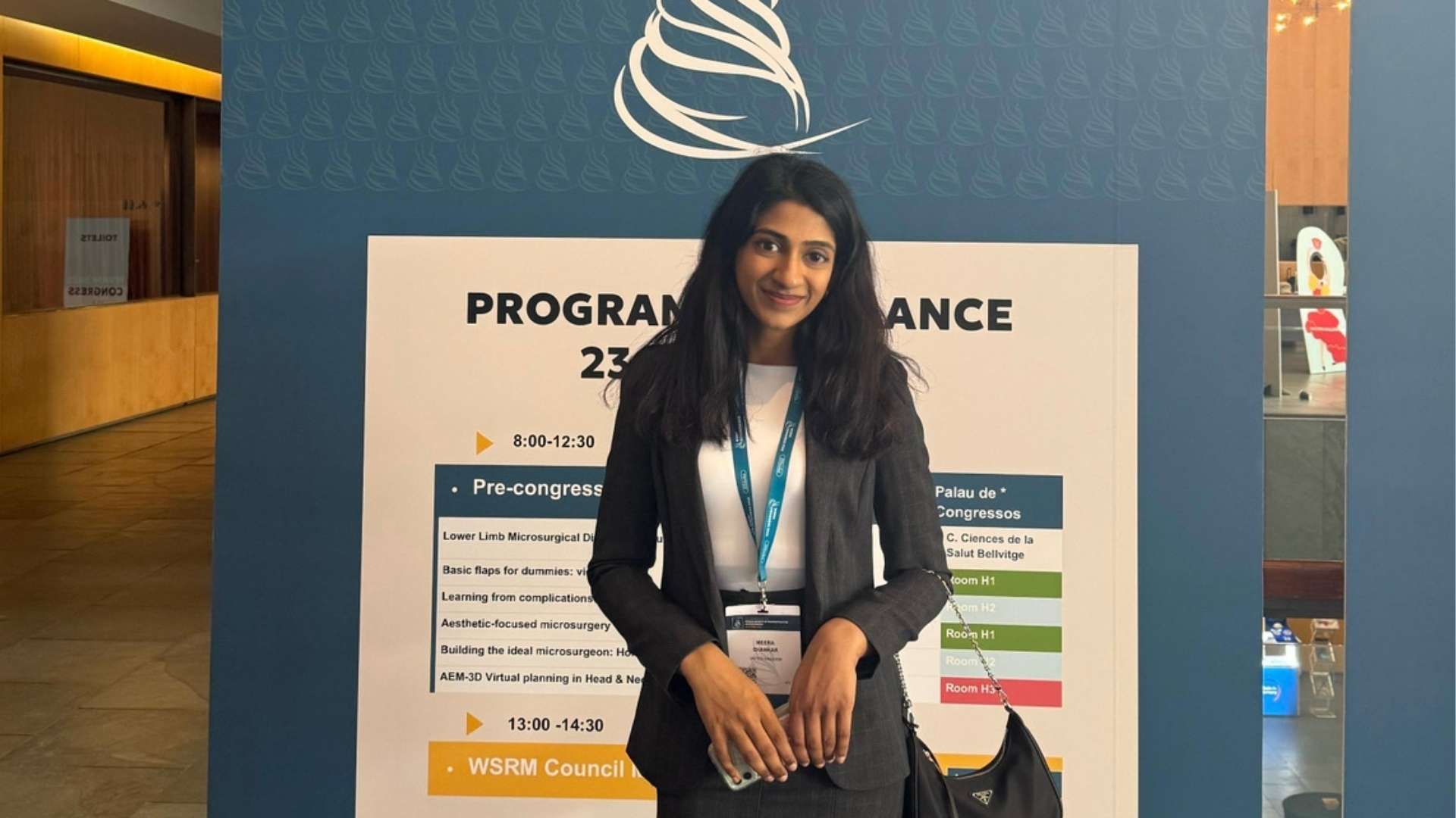 A woman stands in front of a conference program board.