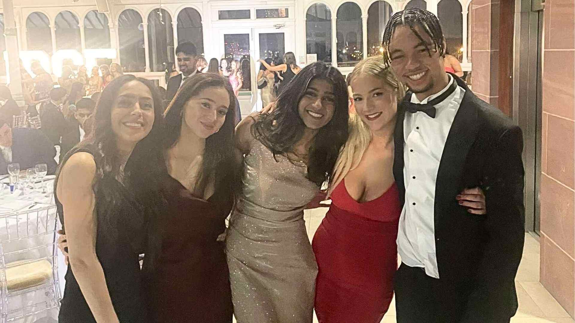 Meera with her friends formal evening wear, smiling and posing together at a glamorous event.
