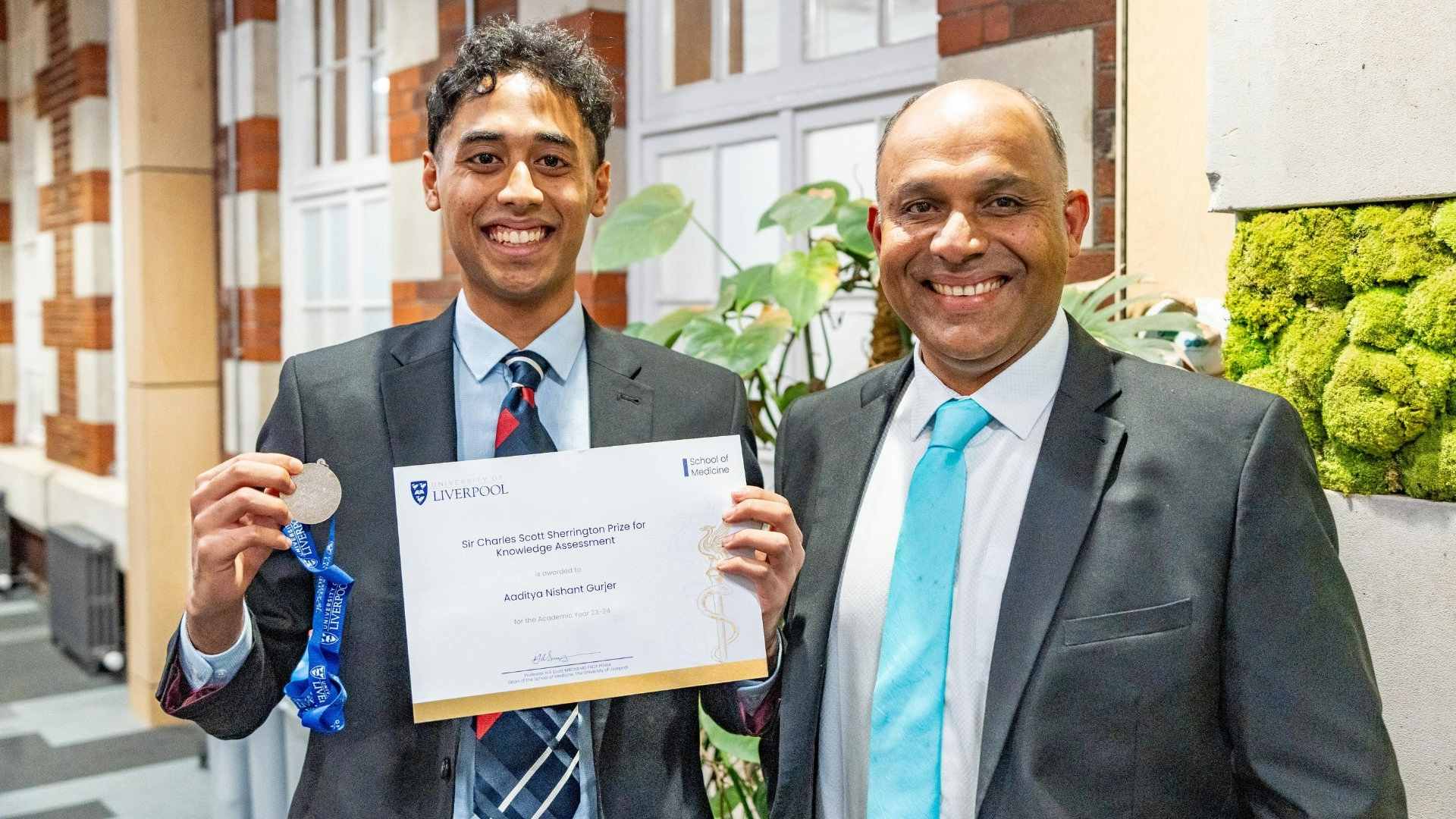 Prize winner Aaditya Nishant Gurjer holding his certificate and medal. Standing next to his Dad