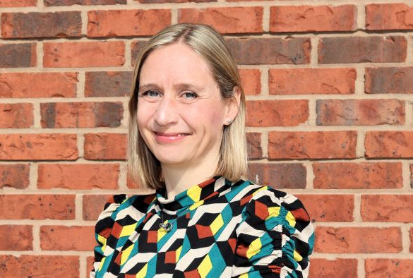 Charlotte Hardman smiles in front of a brick wall