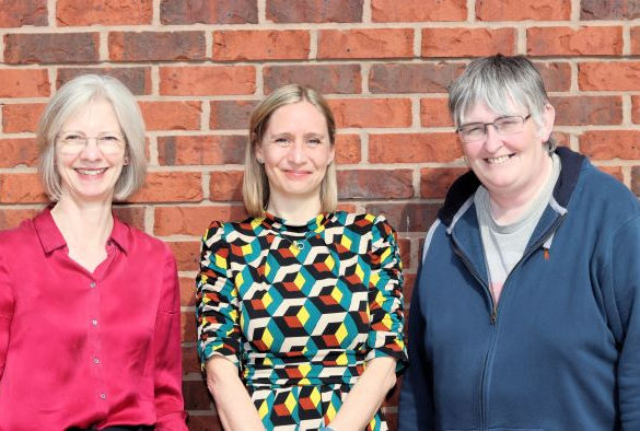 Sally Sheard, Charlotte Hardman and Jo Harrold smile in front of a brick wall