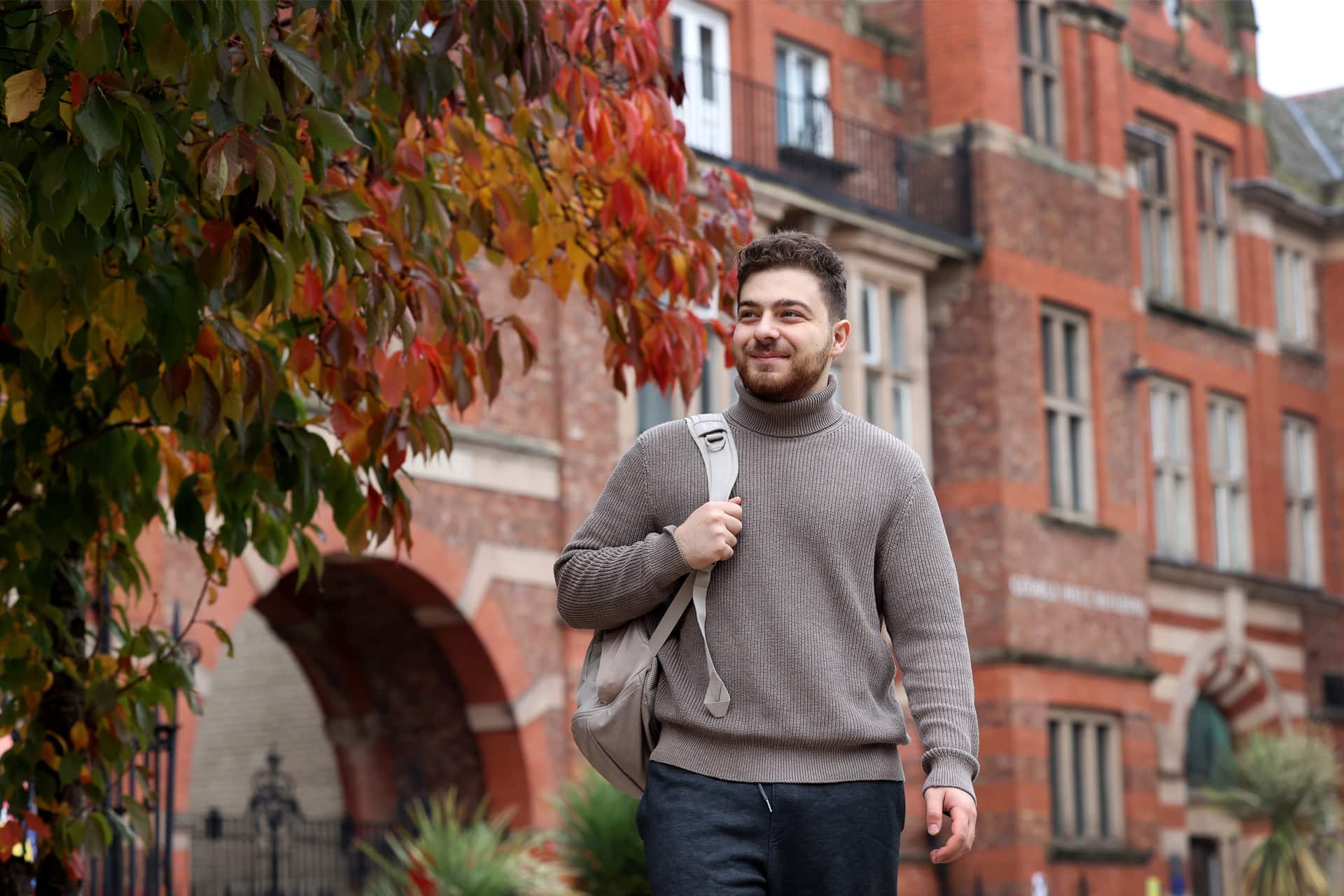 A students walks past a large red brick building.