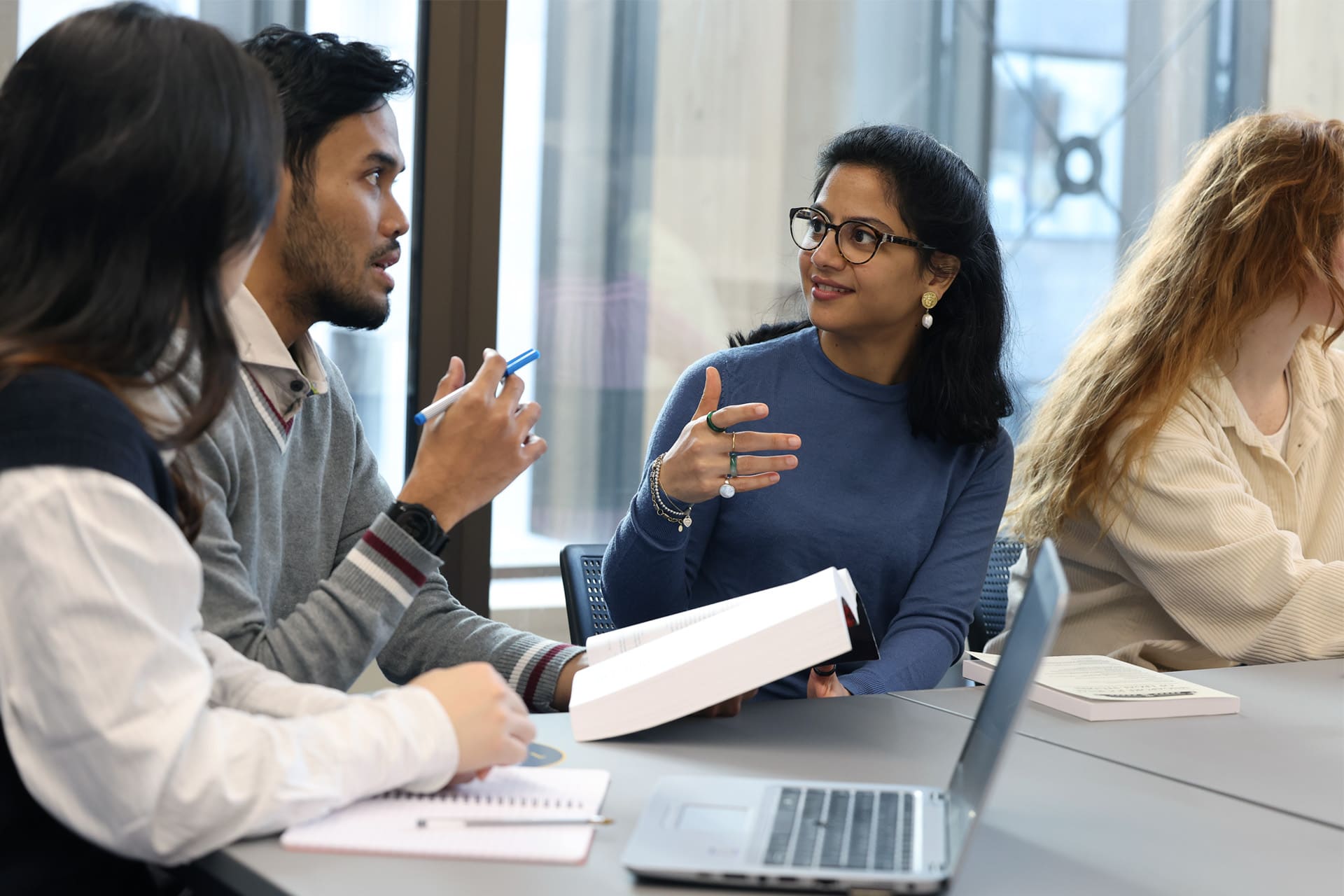 A group of students engaged in conversation around a desk.
