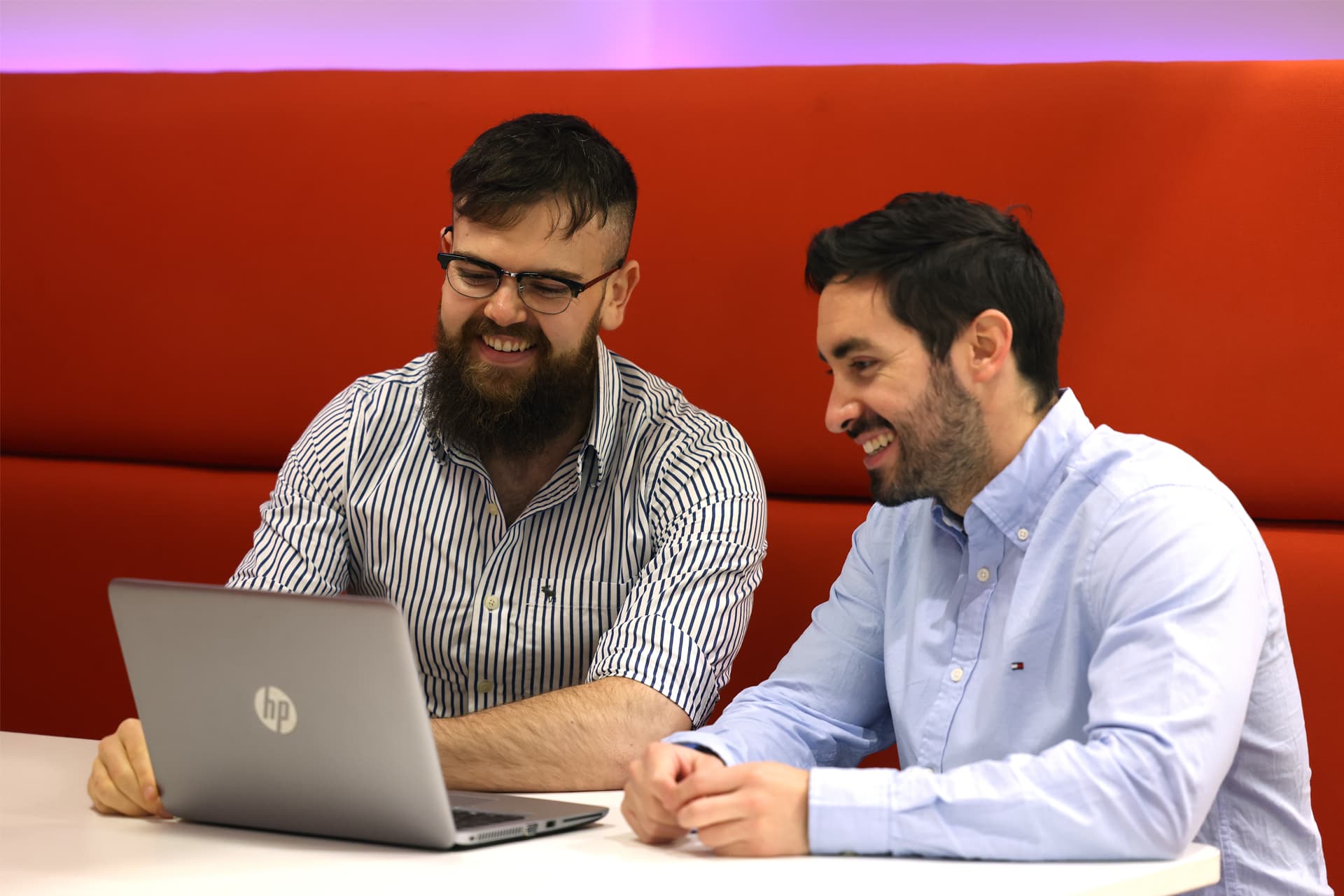 Two students sit working on a laptop together.