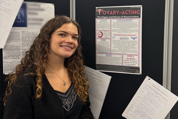 Student Victoria Craddock stands in front of poster board.