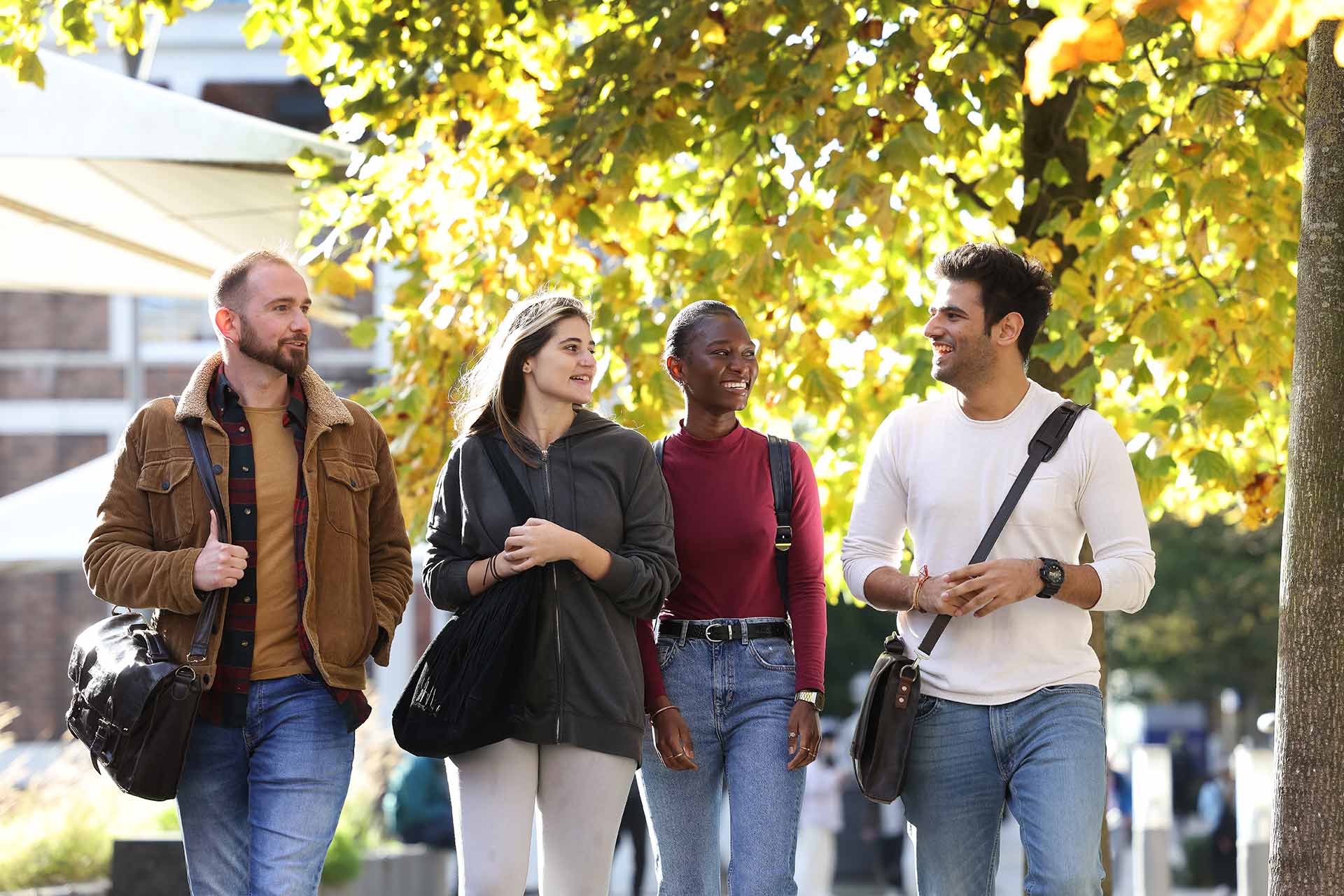 Lee Wainwright, Daniella Trimmis, Namonda Muyunda and Harsh Chaudhary walking on campus - Postgraduate Students (Group shot)