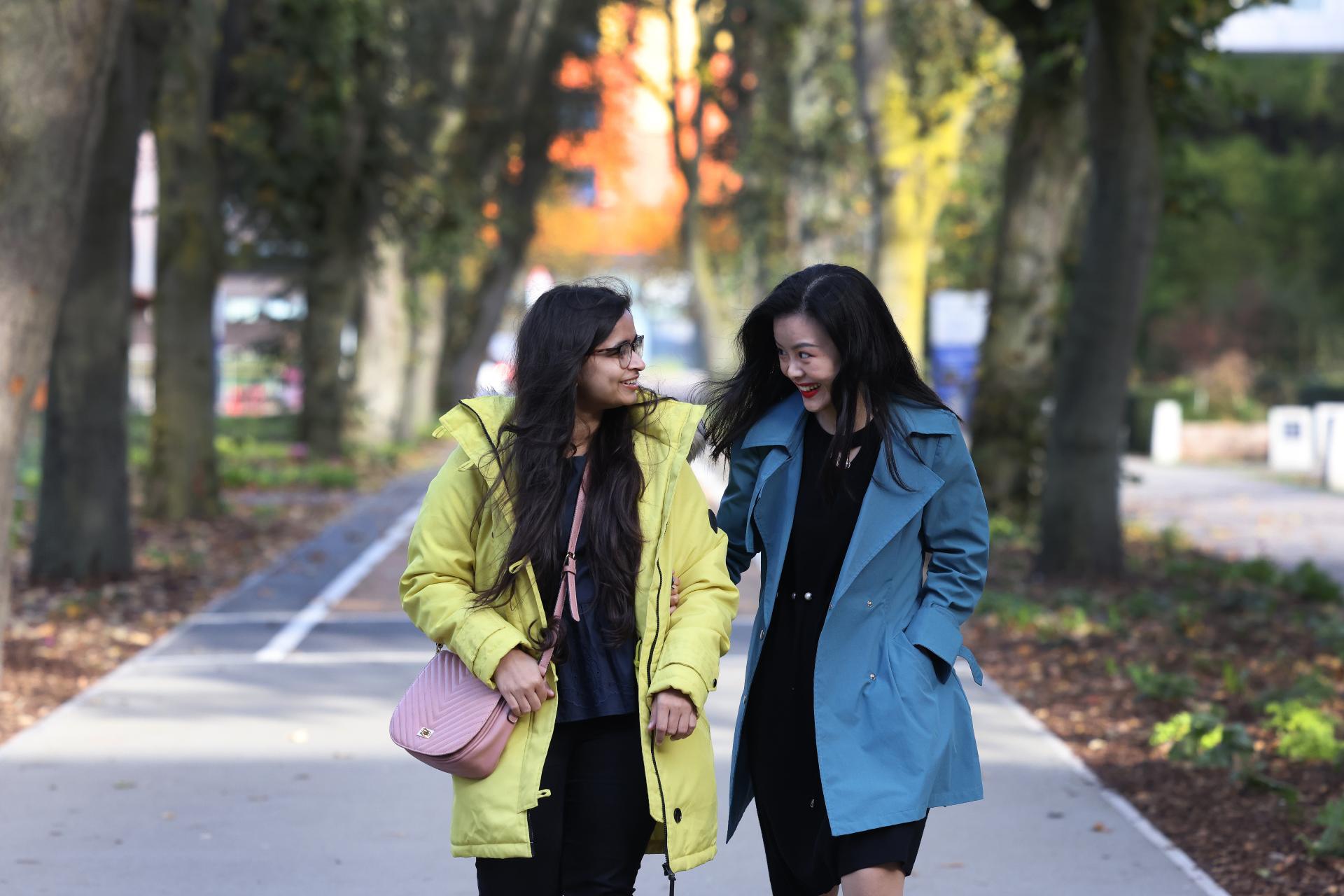 Two students walking through campus and laughing.