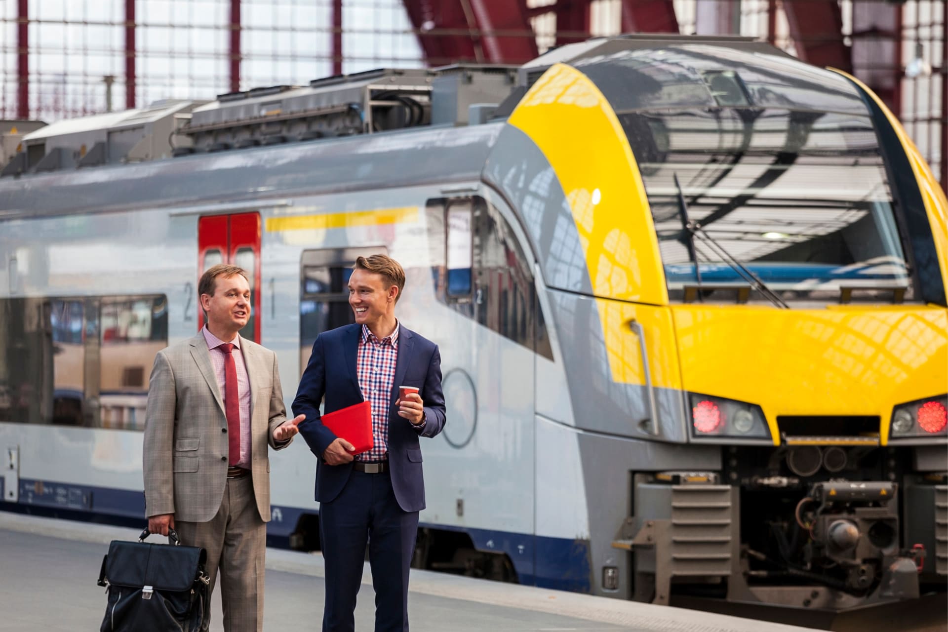 Two men dressed in suits walking near a train.