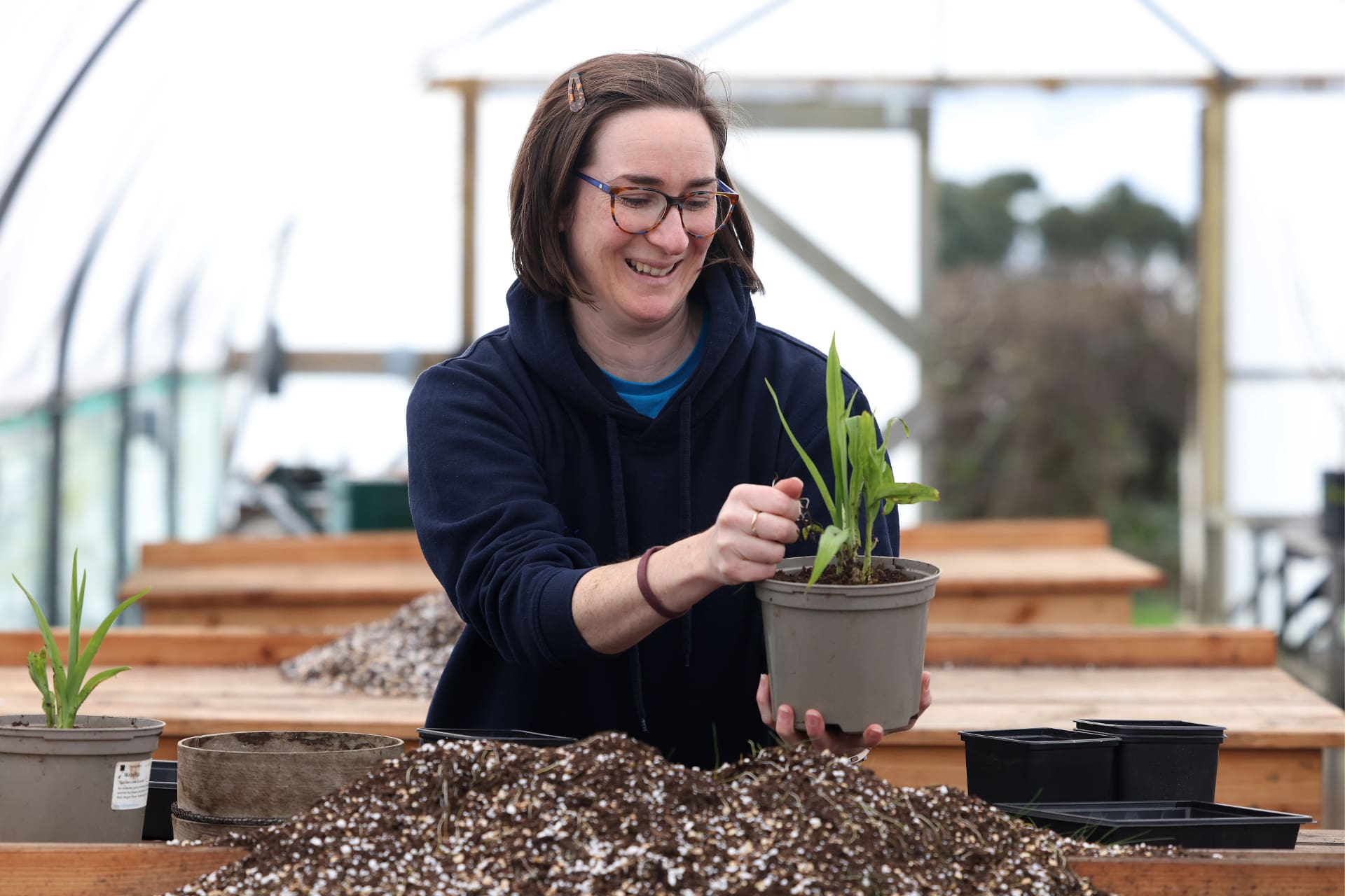 A woman planting a pot with fresh soil.