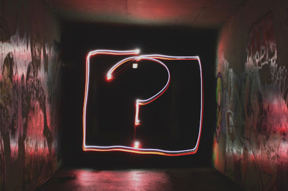 A question mark in neon lights surrounded by graffiti