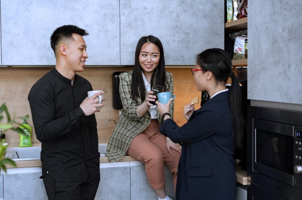 Three people talking and drinking tea in the kitchen