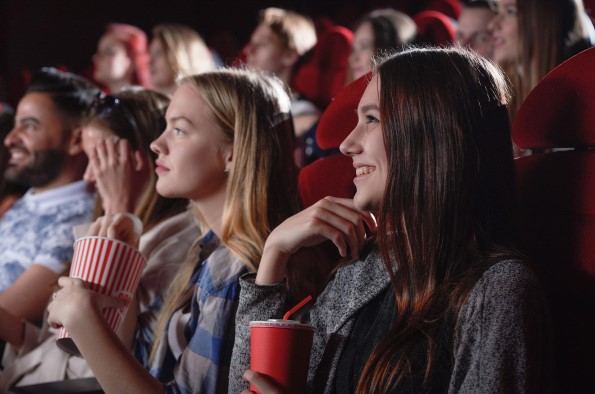 women sat in cinema eating popcorn and drinking soft drink